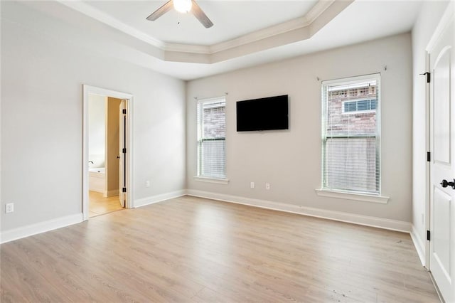 interior space featuring a tray ceiling, ornamental molding, light wood-style flooring, and multiple windows