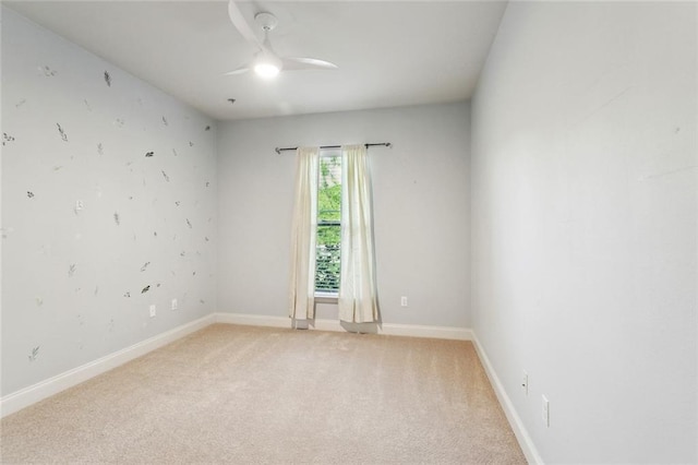 empty room featuring baseboards, a ceiling fan, and light carpet