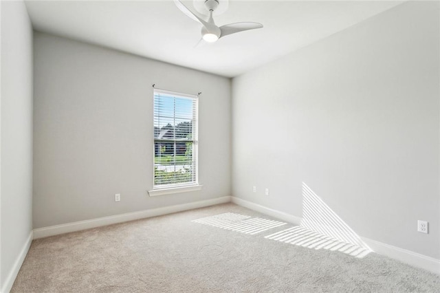 carpeted spare room featuring baseboards and ceiling fan