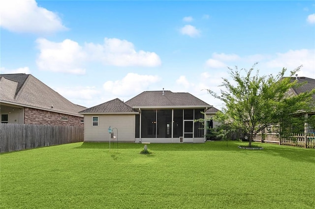 back of house featuring a lawn, a fenced backyard, and a sunroom