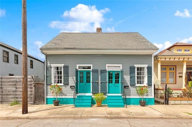 view of front of property featuring fence, a chimney, and entry steps
