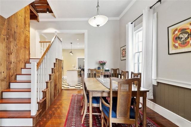 dining room featuring stairway, ornamental molding, wooden walls, and wood finished floors