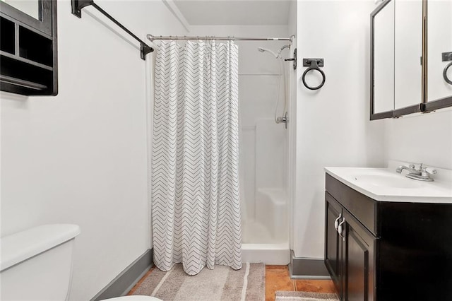 bathroom with vanity, baseboards, toilet, and a shower stall