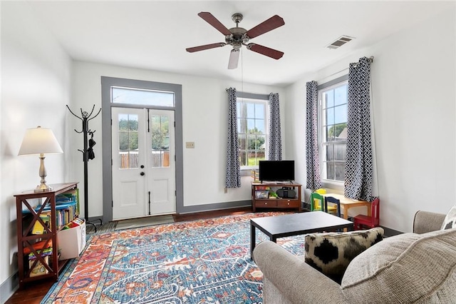 living area with visible vents, a ceiling fan, baseboards, and wood finished floors