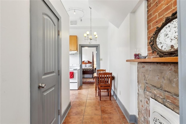 hallway featuring light tile patterned floors, baseboards, an inviting chandelier, and visible vents