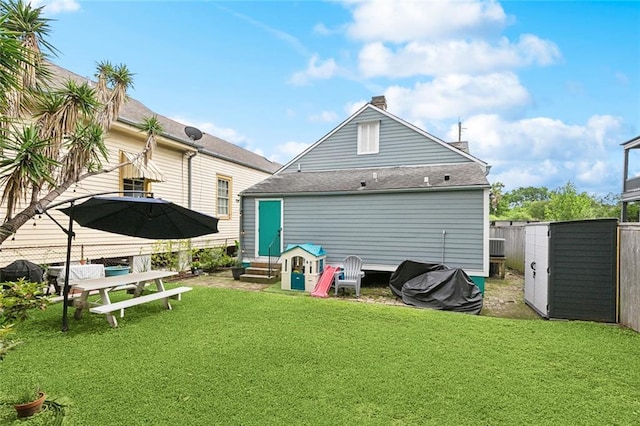 rear view of property with a yard, roof with shingles, a fenced backyard, and entry steps
