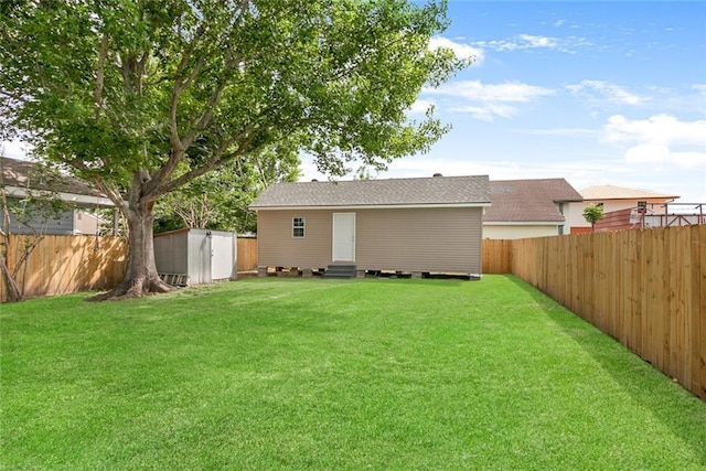 view of yard with entry steps, an outbuilding, a fenced backyard, and a storage shed