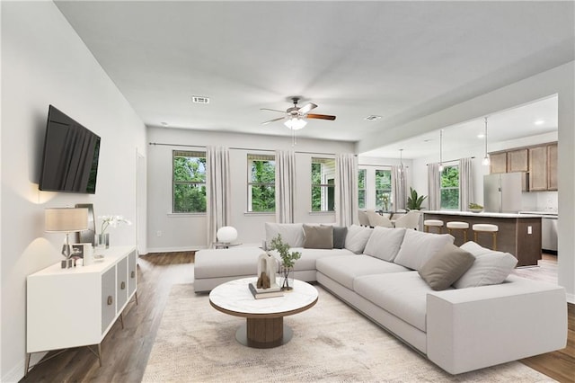 living area with a ceiling fan, wood finished floors, and baseboards