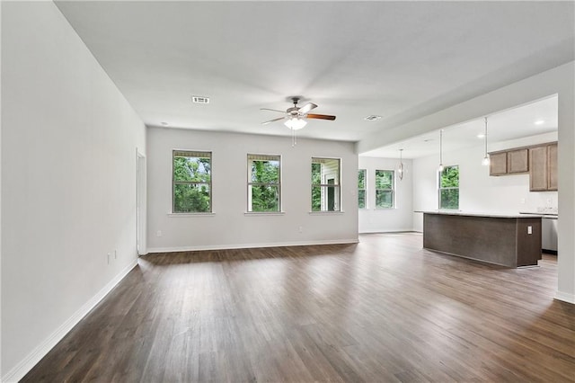 unfurnished living room featuring baseboards, a wealth of natural light, ceiling fan, and dark wood-style flooring