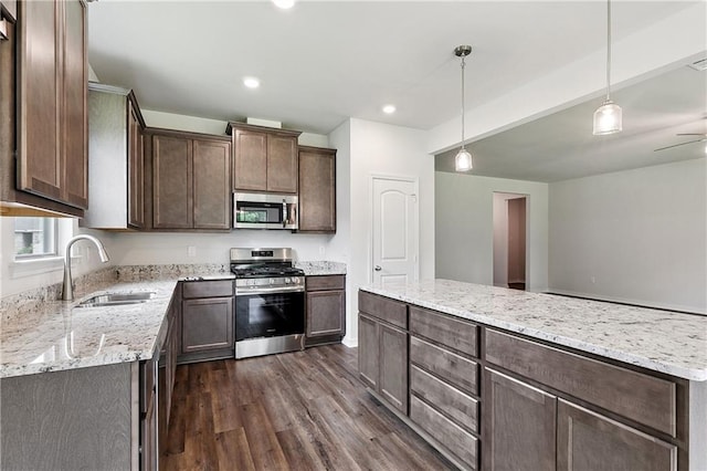 kitchen with dark brown cabinets, light stone counters, dark wood finished floors, a sink, and stainless steel appliances