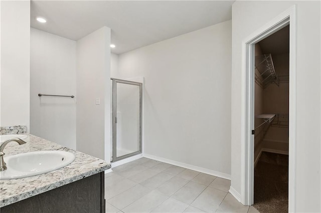 full bath featuring tile patterned floors, baseboards, a shower stall, vanity, and a spacious closet