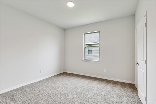 carpeted empty room featuring baseboards