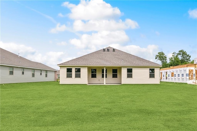 rear view of property with a yard, a patio, and a shingled roof