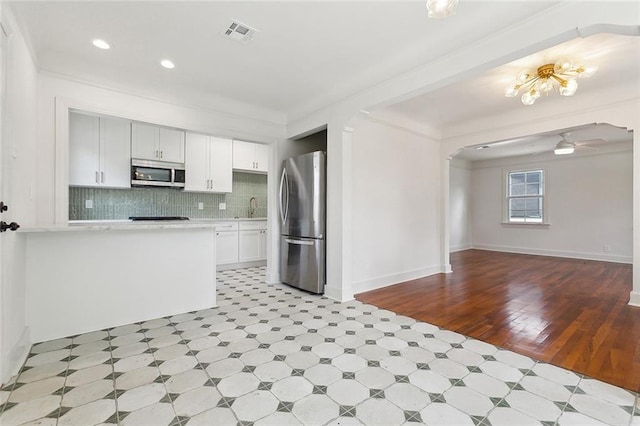 316 Claiborne Ct, Jefferson, LA 70121 - kitchen with light countertops, stainless steel appliances, white cabinetry, decorative backsplash, and visible vents