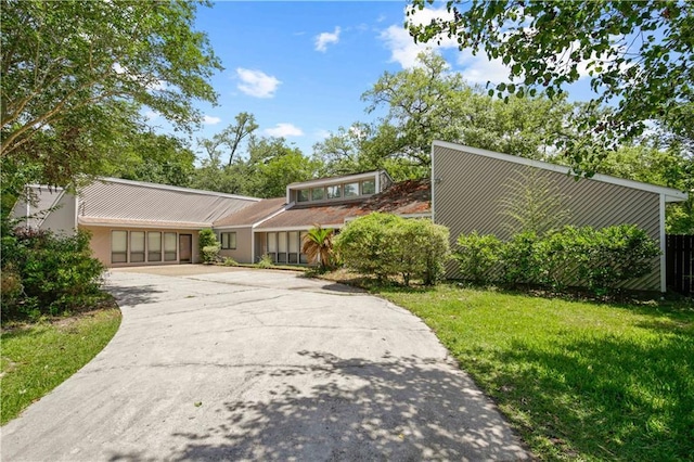 mid-century modern home featuring stucco siding, driveway, and a front yard