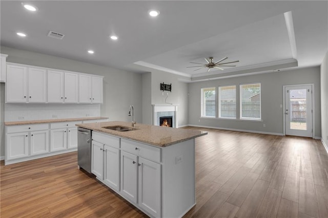 kitchen featuring a raised ceiling, a sink, stainless steel dishwasher, a ceiling fan, and recessed lighting