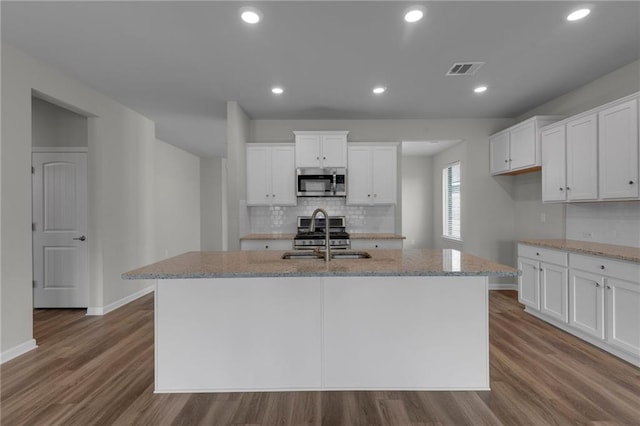 kitchen with stainless steel appliances, a sink, dark wood-type flooring, baseboards, and tasteful backsplash