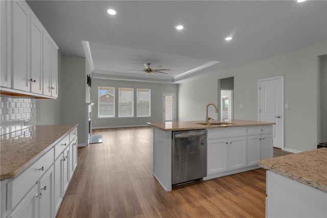 kitchen with stainless steel dishwasher, a sink, a kitchen island with sink, ceiling fan, and white cabinets