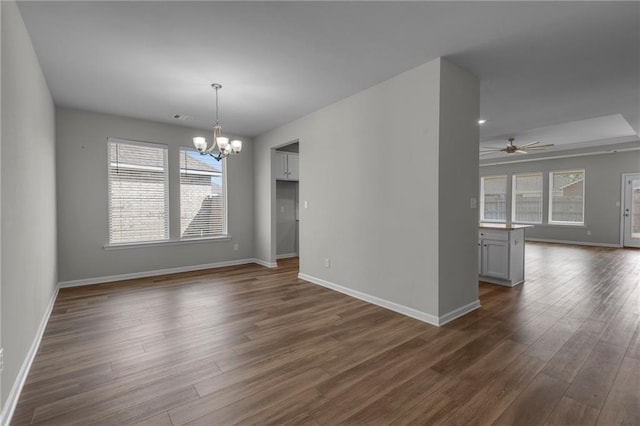 unfurnished dining area featuring a chandelier, dark wood-style floors, ceiling fan, and baseboards