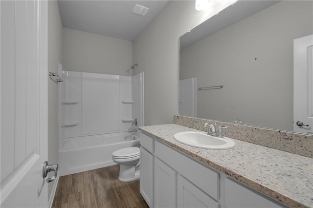 bathroom featuring wood finished floors, vanity, toilet, and shower / tub combination