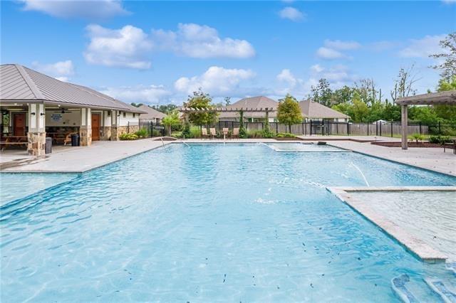 community pool with fence, a patio area, and a ceiling fan