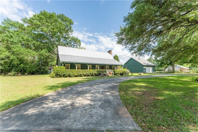 view of front of house with a garage, a front lawn, covered porch, a chimney, and driveway