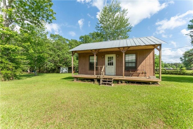 exterior space with a porch, a yard, and metal roof