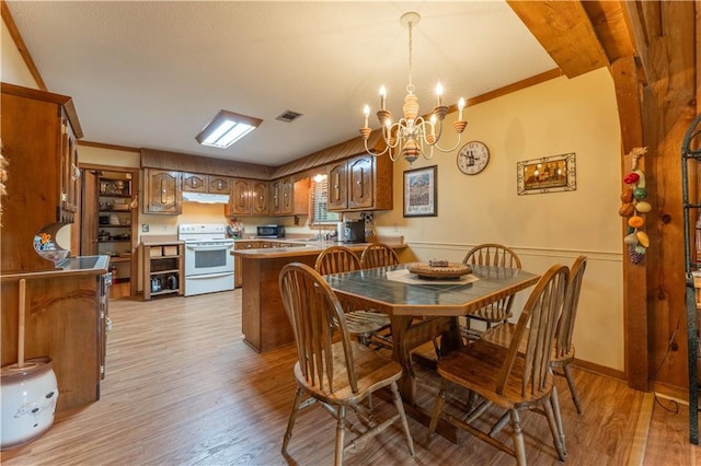 dining room with a notable chandelier, wainscoting, light wood-style floors, visible vents, and ornamental molding