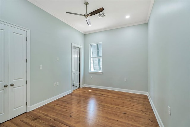 unfurnished bedroom featuring ceiling fan, visible vents, wood finished floors, baseboards, and ornamental molding