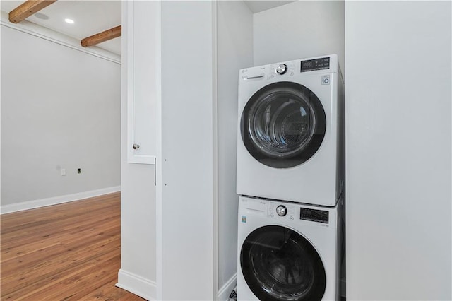 clothes washing area featuring laundry area, recessed lighting, baseboards, stacked washer / dryer, and wood finished floors