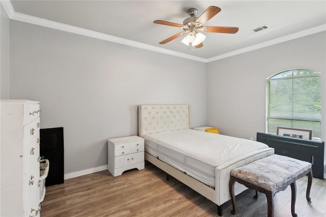 bedroom with a ceiling fan, visible vents, light wood-type flooring, baseboards, and ornamental molding