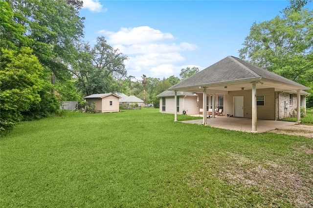 back of property with a patio, a shed, an attached carport, a lawn, and driveway
