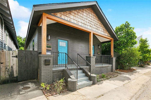 bungalow with a porch, fence, and a gate