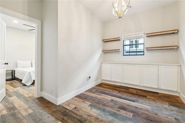 unfurnished room featuring baseboards, dark wood finished floors, and an inviting chandelier