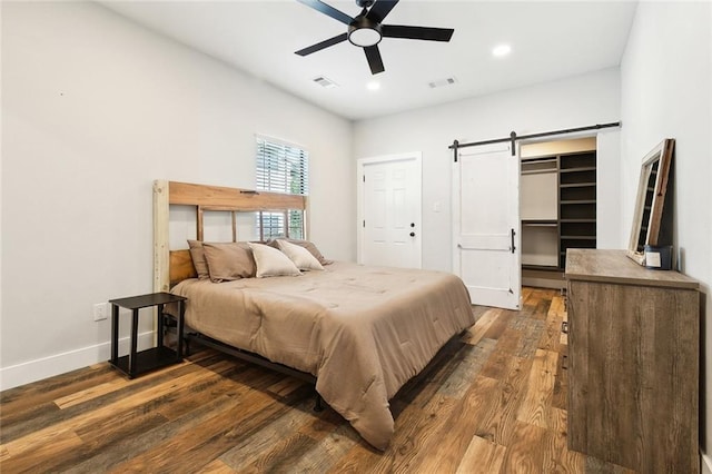 bedroom with visible vents, a barn door, dark wood-style floors, and recessed lighting