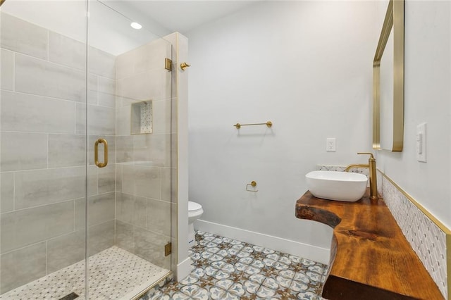 full bathroom with toilet, baseboards, a shower stall, and a sink