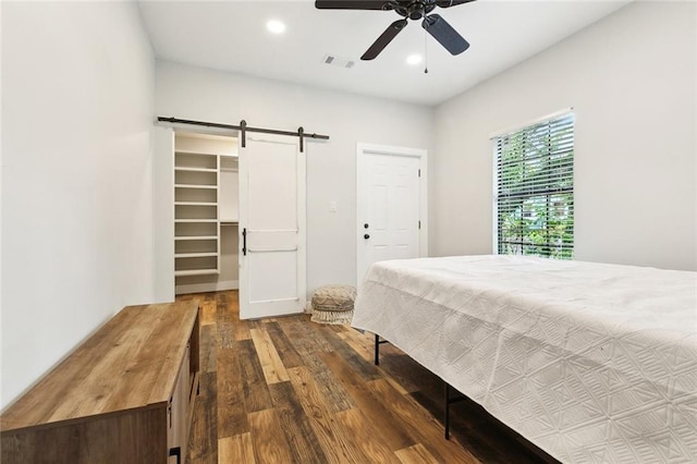 bedroom with visible vents, a barn door, wood finished floors, a spacious closet, and recessed lighting