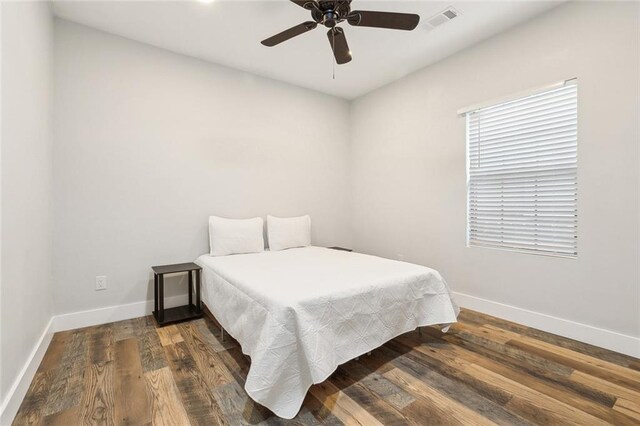 bedroom with baseboards, a ceiling fan, wood finished floors, and visible vents