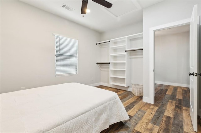 bedroom featuring visible vents, a closet, wood finished floors, baseboards, and a ceiling fan