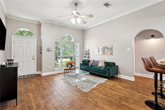 living area with a ceiling fan, visible vents, arched walkways, wood finished floors, and baseboards