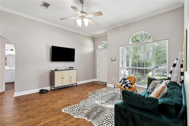 living area featuring arched walkways, wood finished floors, and visible vents