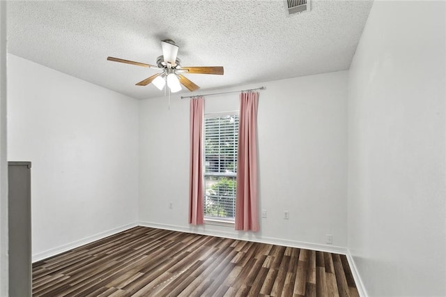 spare room with visible vents, a ceiling fan, dark wood-style flooring, and baseboards