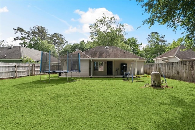 back of property featuring a fenced backyard, a trampoline, and a yard