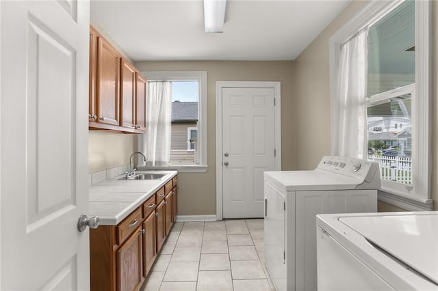 5652 General Haig St, New Orleans, LA 70124 - laundry area featuring washer and dryer, cabinet space, a sink, baseboards, and light tile patterned floors