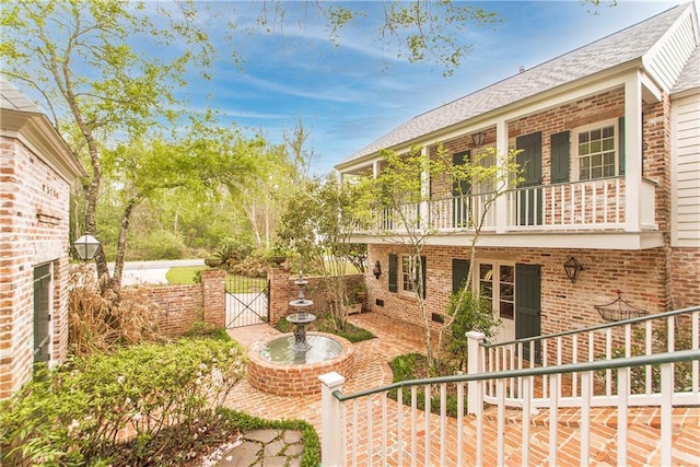 view of yard featuring a gate, a balcony, and fence