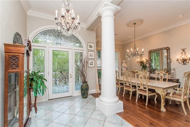 foyer featuring a chandelier, decorative columns, crown molding, and light tile patterned floors