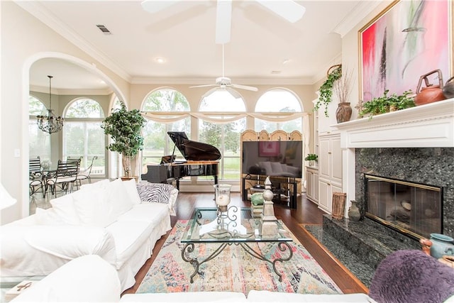 living area with dark wood-type flooring, a ceiling fan, a high end fireplace, and ornamental molding