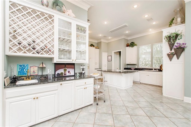 kitchen featuring a sink, ornamental molding, glass insert cabinets, white cabinetry, and light tile patterned flooring