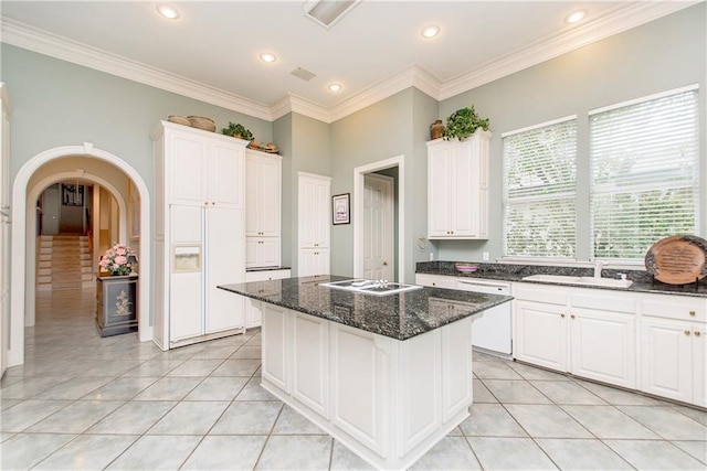 kitchen with light tile patterned flooring, white cabinetry, a kitchen island, white appliances, and a sink