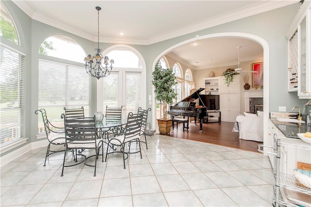 dining room featuring light tile patterned floors, healthy amount of natural light, crown molding, arched walkways, and a chandelier